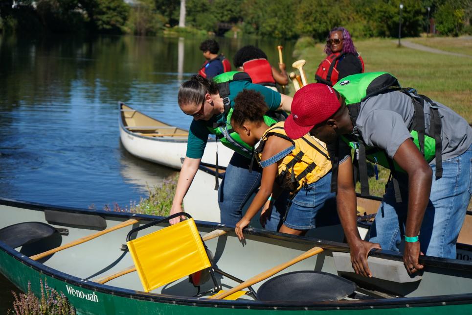 A family puts their canoe in the water before getting in to paddle.