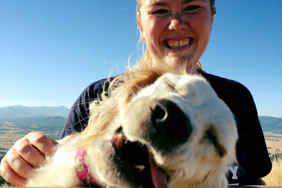 A large dog face with tongue out, and owner smiling.
