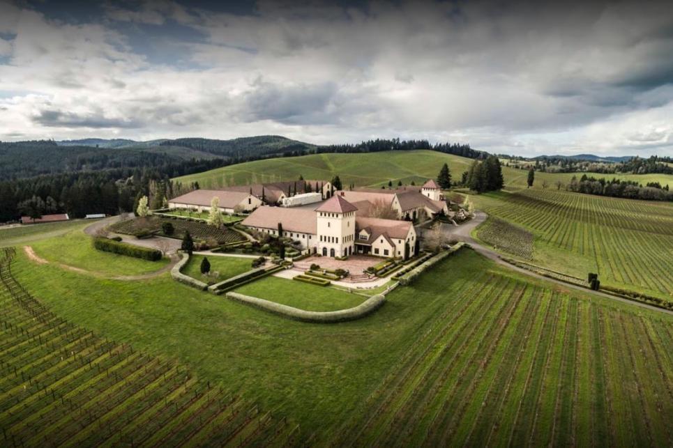 An aerial photo of the castle-like King Estate tasting room surrounded by green vineyards and distant mountains