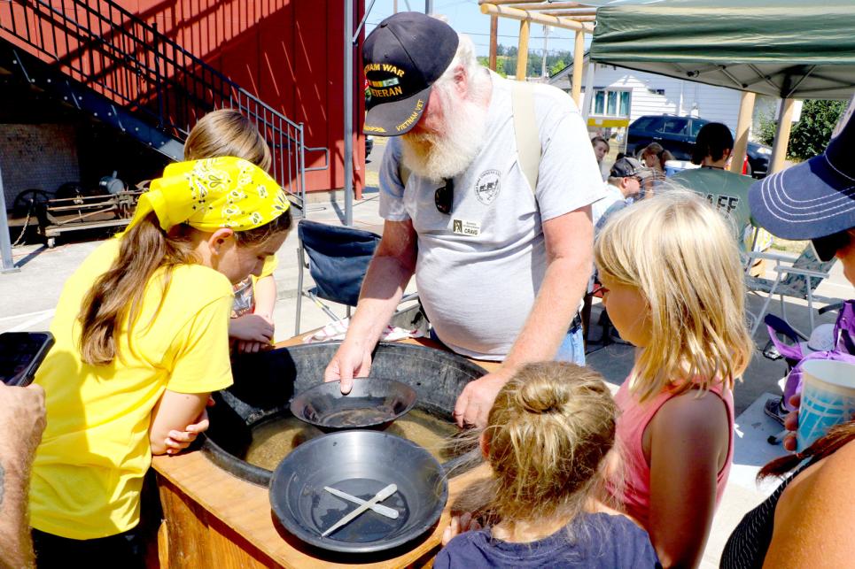 Children gather around a gold panning demonstration.