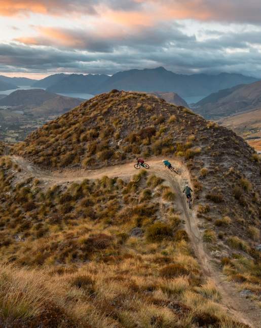 Mountain bikers riding at the top of a mountain with views of the basin in the background