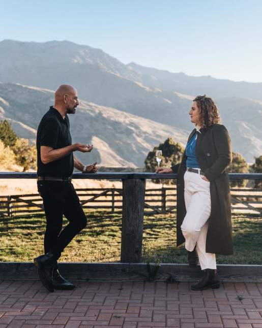 Two people networking outside with a glass of champagne and mountain view in the background
