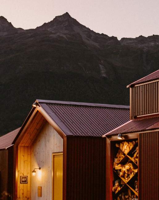 Exterior shot of Great Glenorchy Alpine Base Camp wood and tin building with mountains in the background at dusk