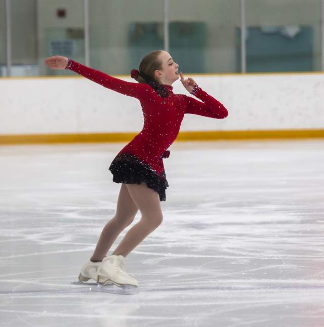 A solo skater posing on ice during her routine.