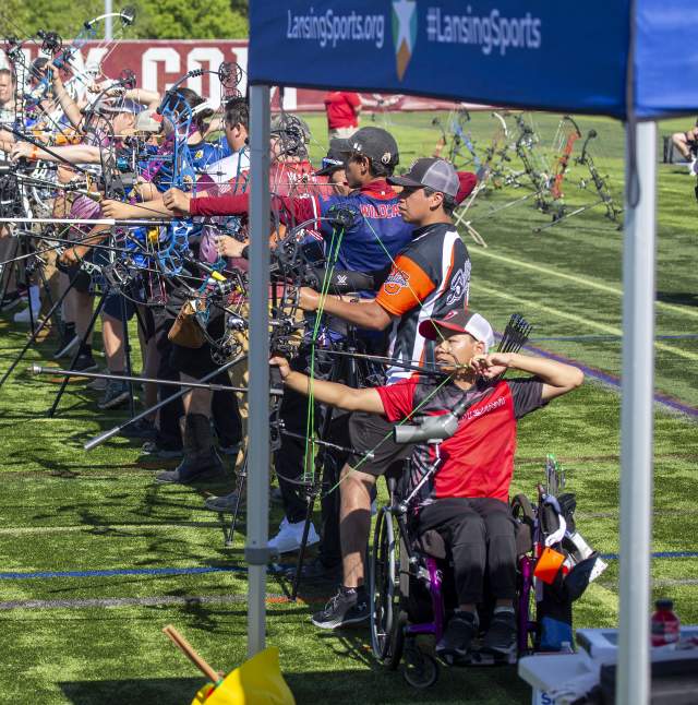 A group of archers line up and aim at the targets.