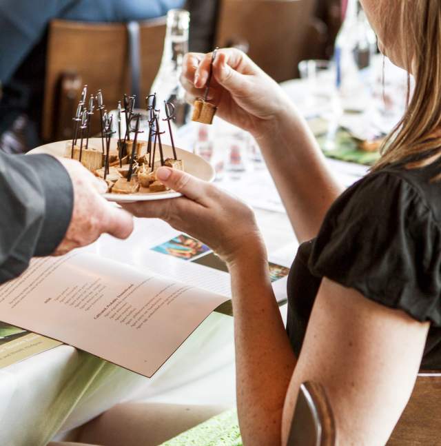 Woman at a table being served sample food on a tray