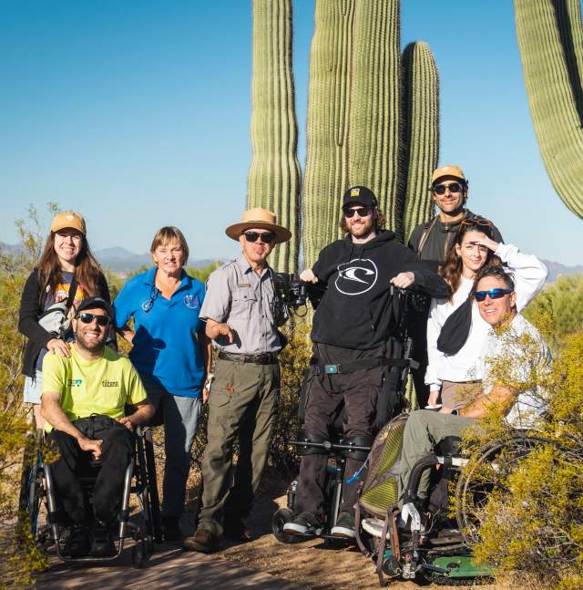 Group of people in the desert, surrounded by saguaros