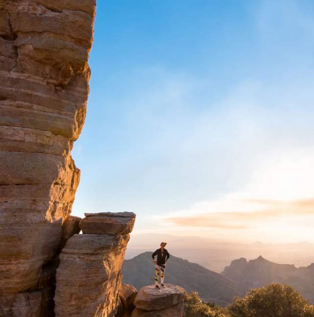 Woman standing beside tall rock formation at Windy Point Vista in Tucson looking to the horizon