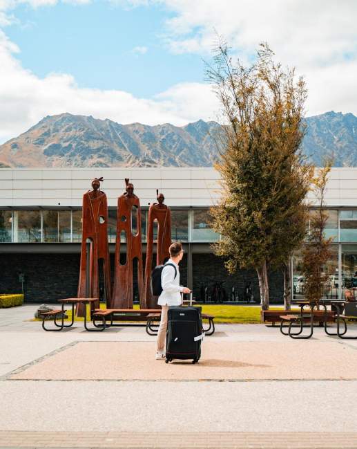 Exterior of airport with traveler walking past with suitcase
