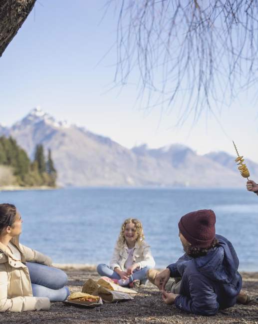 Family eating fish and chips at Queenstown Bay beach