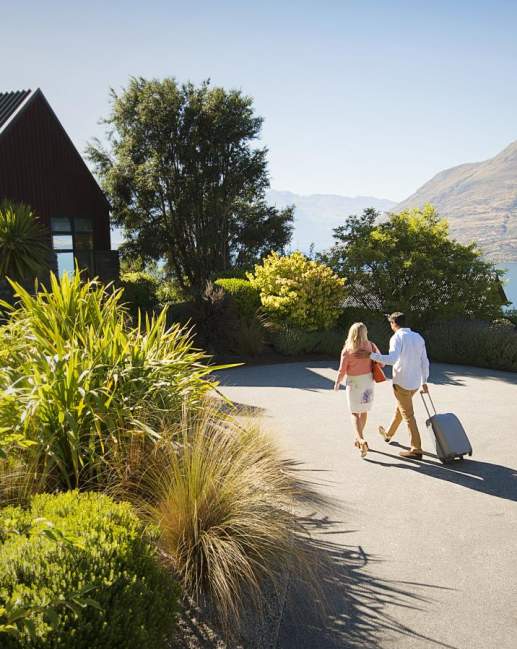 Couple wheeling a suitcase to their Queenstown accommodation