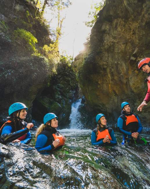 Group of people in wetsuits and helmets in the middle of a canyon