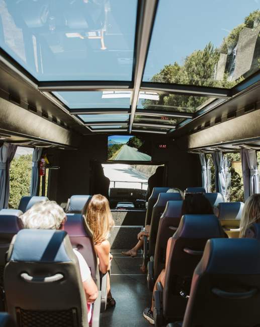 Inside shot of a tour bus driving along a scenic road