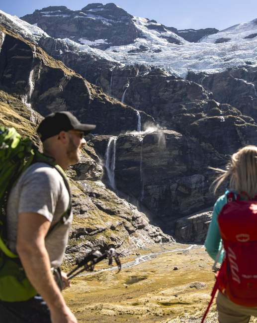 Couple hiking underneath glacier at Earnslaw Burn