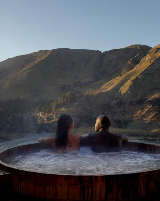 Two people in a hot tub with a beautiful mountain view