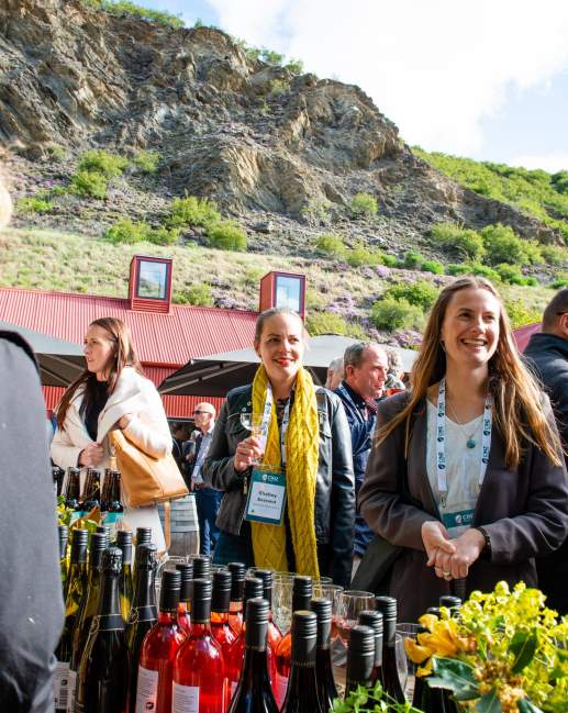 A group of conference attendees standing around a wine tasting table