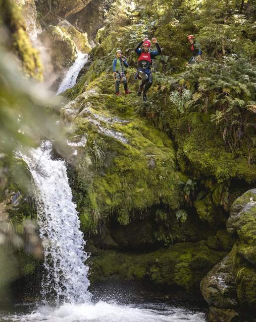 Person canyoning, jumping off a waterfall into a natural spring
