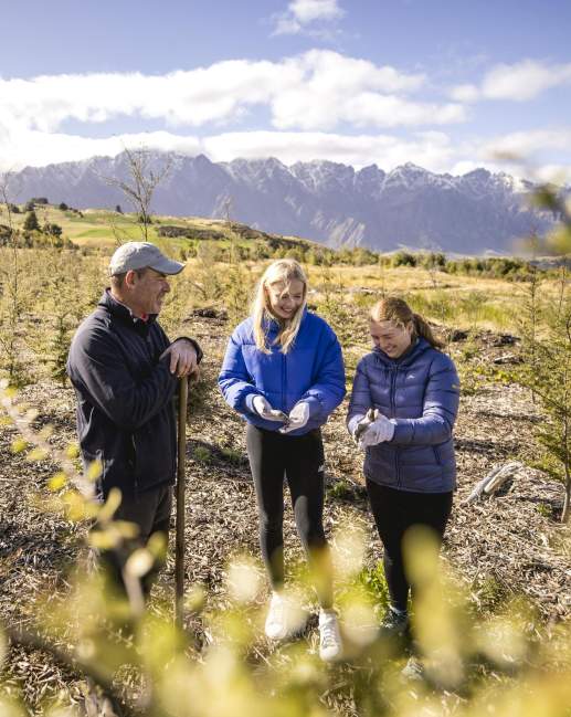 3 people working at a planting site in Queenstown, planting native trees to reforest the area with native bush