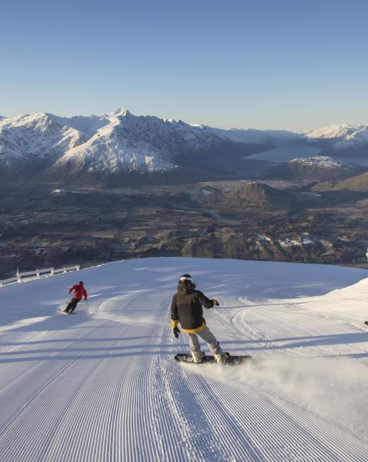 Snowboarders and skiers riding down snowy mountain