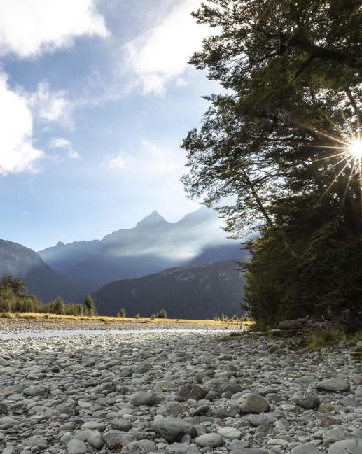 Scenic photo of a river and mountains from a rocky shore