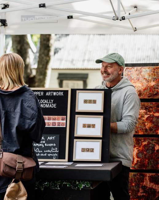 Women purchasing local artwork at the Arrowtown Farmers Market