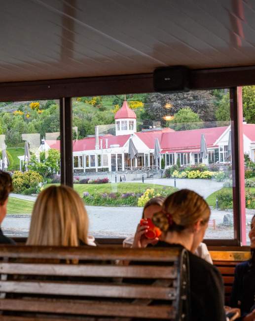 A group of people sitting on the TSS Earnslaw with a view of Walter Peak through the windows