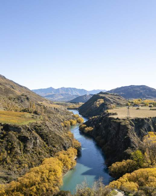 Aerial of the Kawarau River snaking through mountains and vineyards in Gibbston