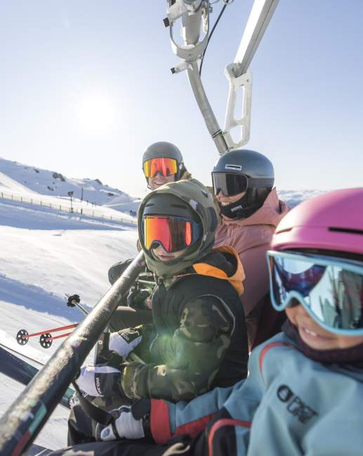 Family in ski gear sitting on a chair lift at Cardrona Ski Resort
