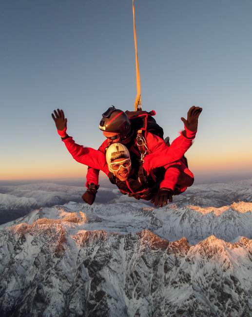 Skydiver high above snowcapped mountains of Queenstown