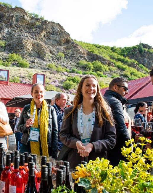 A group of conference attendees standing around a wine tasting table