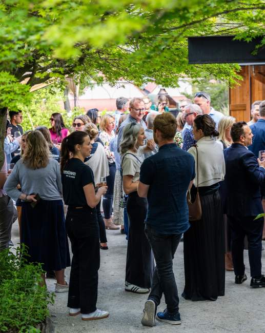 A group of people mingling outside at the Sherwood with trees surrounding the frame