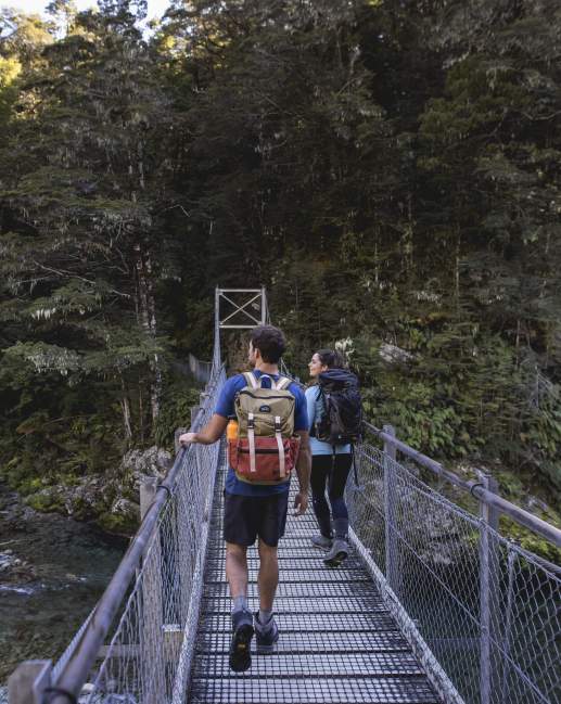 People crossing bridge into native bush at the start of the Routeburn Track