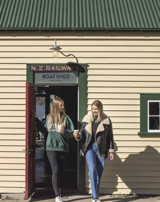 Two people walking out of the Boat Shed Café with keep cups