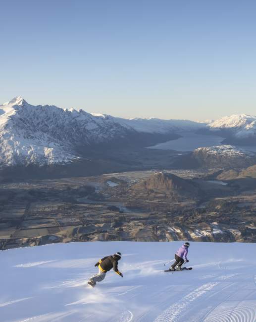 Snowboarding at Coronet Peak with lake and mountains in background