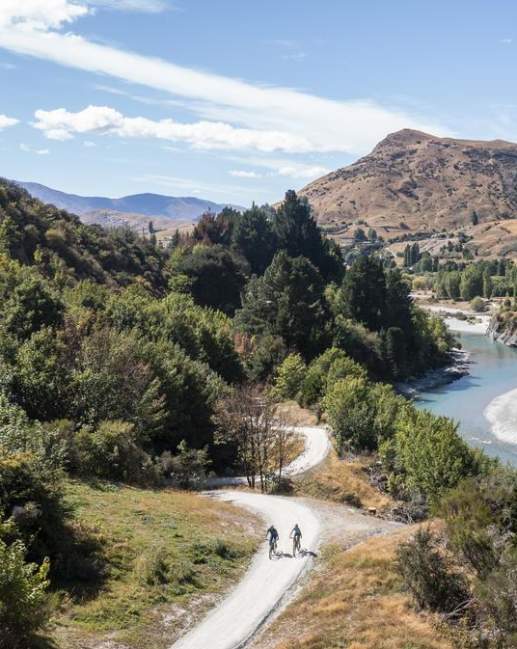 Aerial view of the Shotover Gorge Trail,with two bikers cycling next to a blue river in a Canyon
