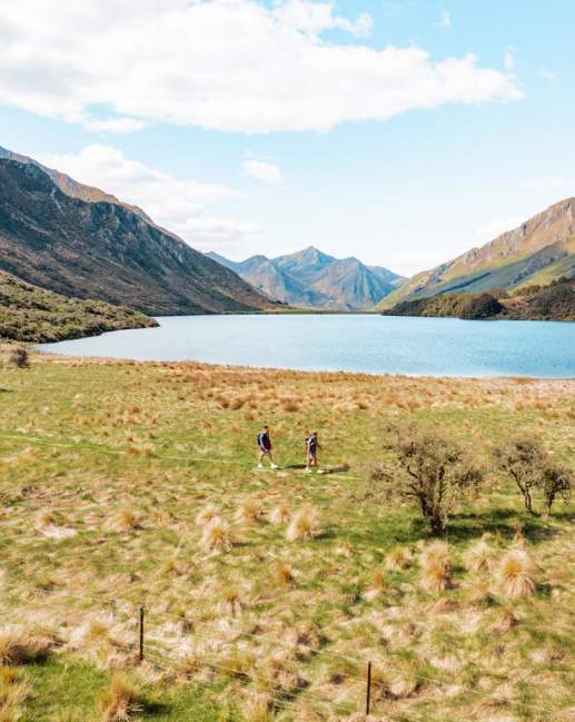 Two people walking Moke Lake Loop Track with lake and mountains in view