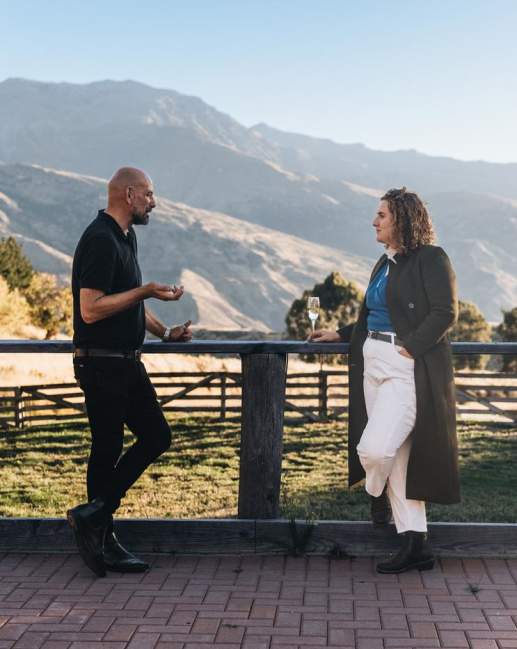 Two people networking outside with a glass of champagne and mountain view in the background