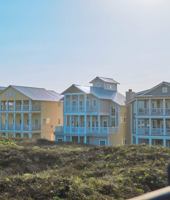 row of 4 large beach houses nestled in dunes in bright sunlight