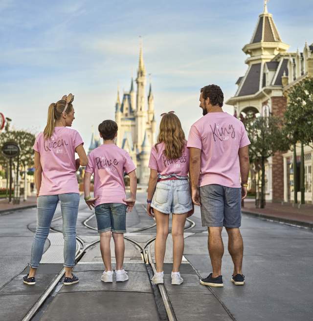 A family of four, in matching pink shirts, walking on Main Street at the Magic Kingdom in the Walt Disney World Resort.