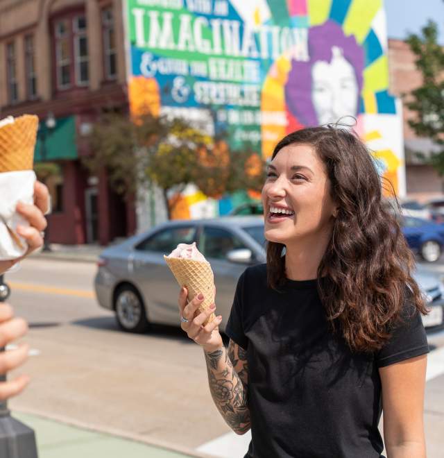 women laughing with ice cream in front of mural