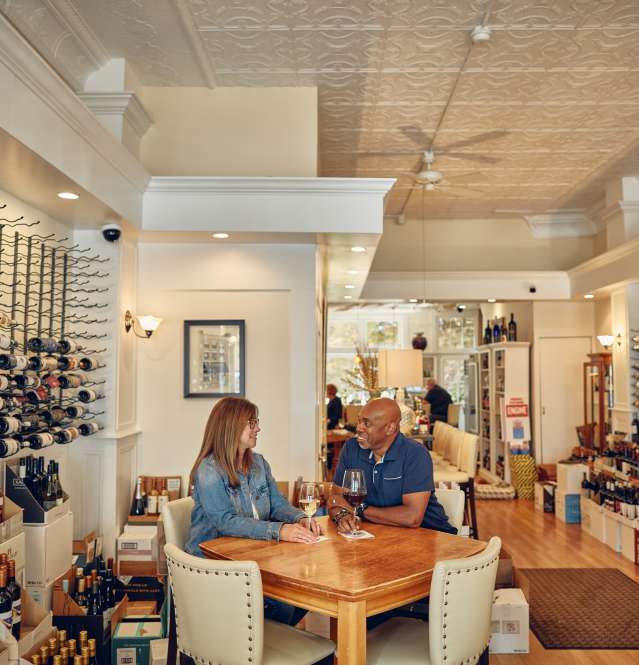 Two people sitting at a table in a wine bar.