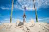 A man carries his toddler daughter on his shoulders and they pose atop a large sand mountain carved with an eagle