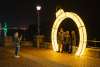 family poses for a photo under a large holiday light exhibit along a riverwalk