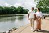 a man and woman walk along a riverside path