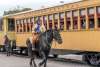 cowboy riding a horse next to a northern central railway train
