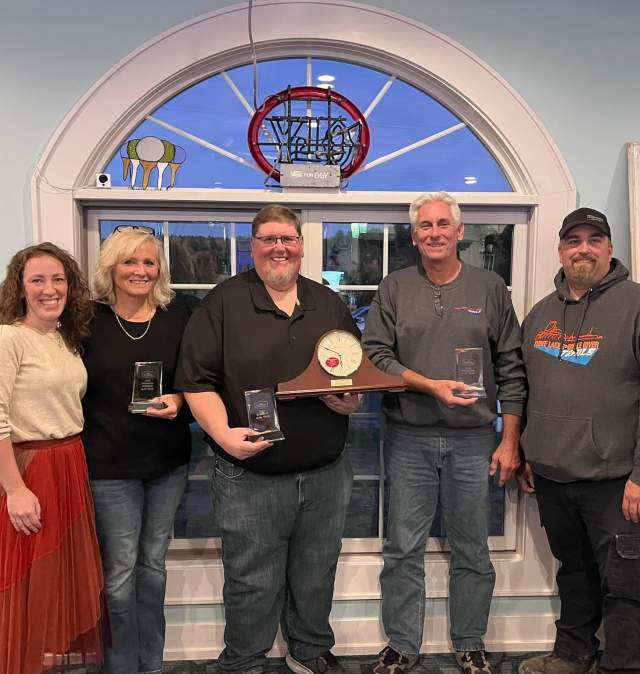 two women and three men line up holding glass awards