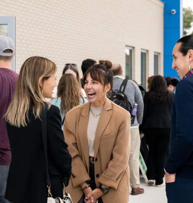 Group of people outside the Discover Green Bay visitor center chatting and laughing.