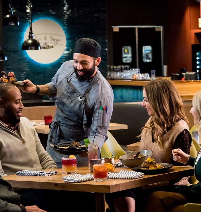 Chef serves a group of diners at Cedar and Sage restaurant in Green Bay.