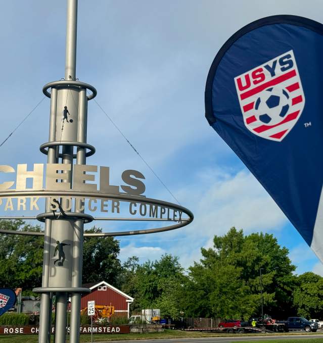 A US Youth Soccer banner waves in front of the Scheels Overland Park Soccer Complex sign