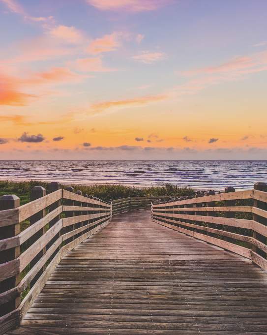 A wooden boardwalk leading to the beach at sunrise